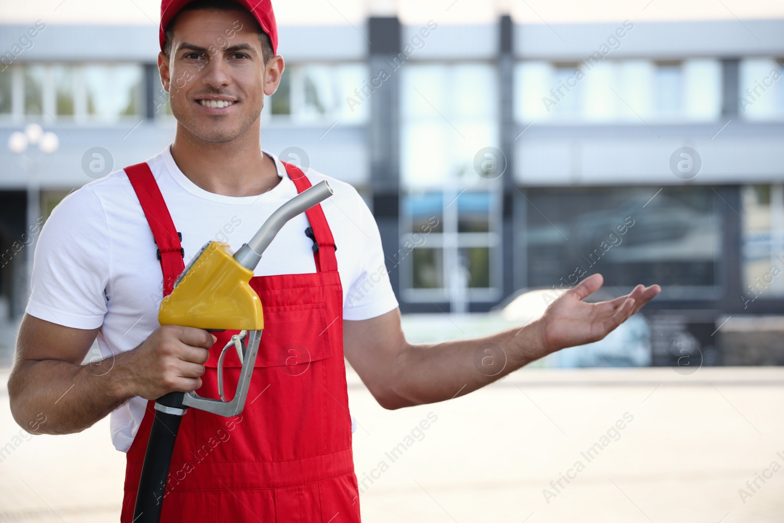 Photo of Worker with fuel pump nozzle at modern gas station