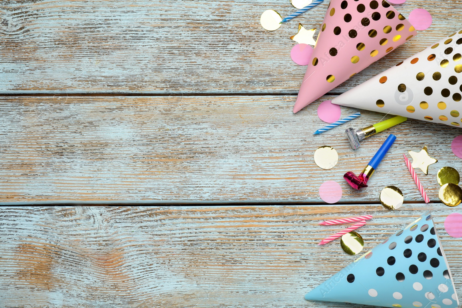 Photo of Colorful party hats and other festive items on wooden table, flat lay. Space for text