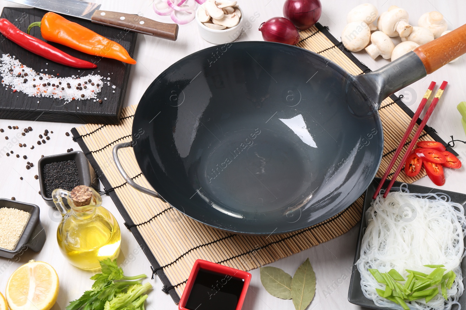 Photo of Wok, chopsticks and different products on white wooden table