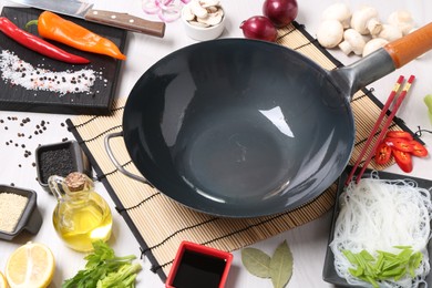 Photo of Wok, chopsticks and different products on white wooden table