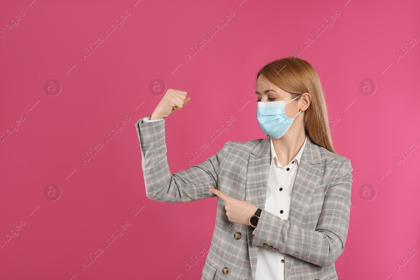 Photo of Businesswoman with protective mask showing muscles on pink background, space for text. Strong immunity concept