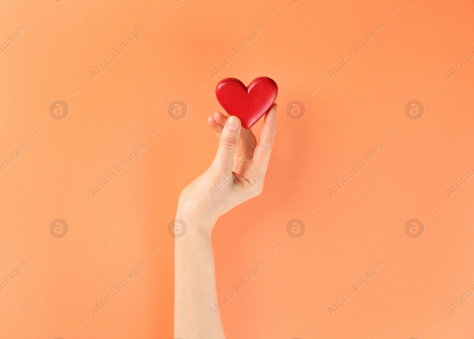 Photo of Woman holding decorative heart on color background, top view