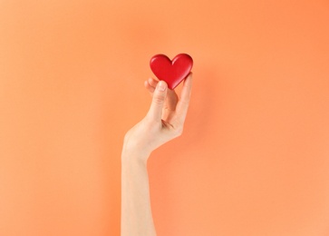 Photo of Woman holding decorative heart on color background, top view