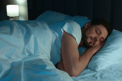 Photo of Handsome man sleeping in bed at night