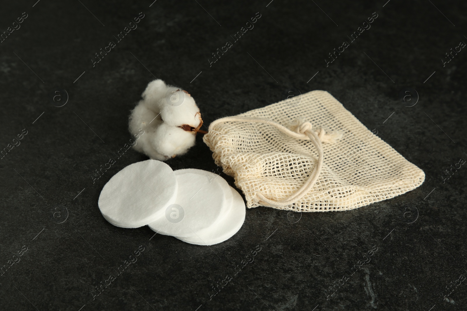 Photo of Cotton pads, bag and flower on black table