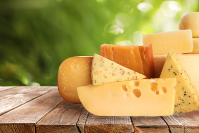 Image of Different types of delicious cheeses on wooden table outdoors. Dairy products