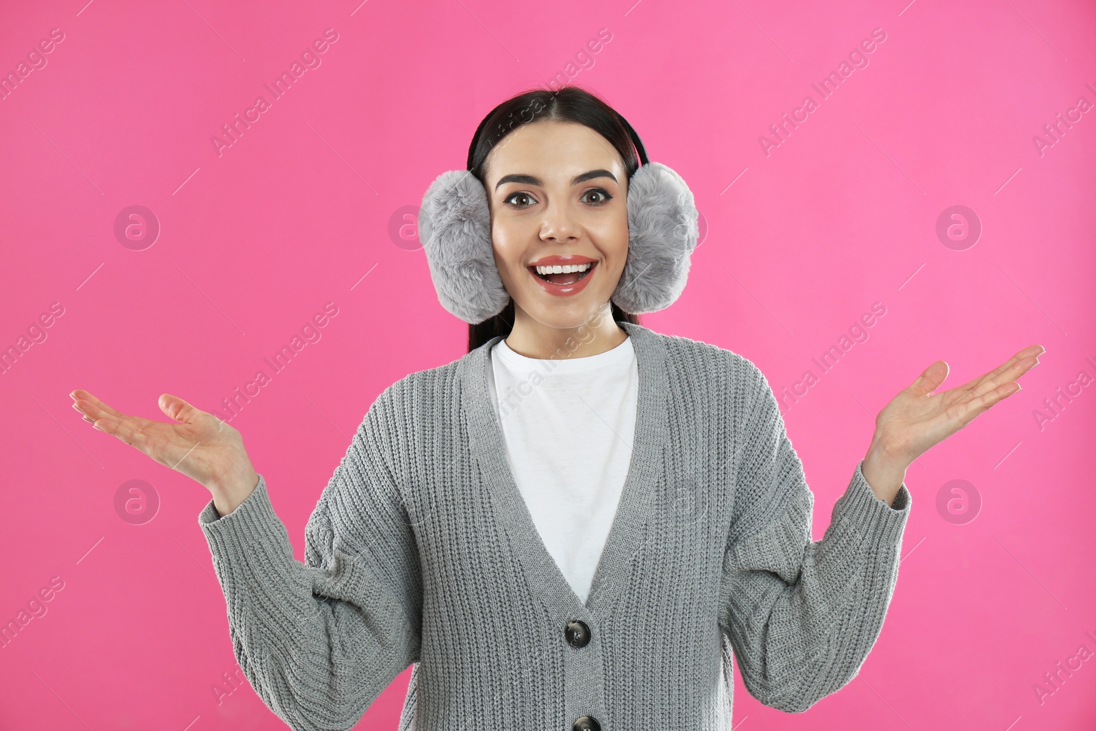 Photo of Beautiful young woman wearing earmuffs on pink background