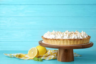Photo of Stand with delicious lemon meringue pie on blue wooden table, space for text
