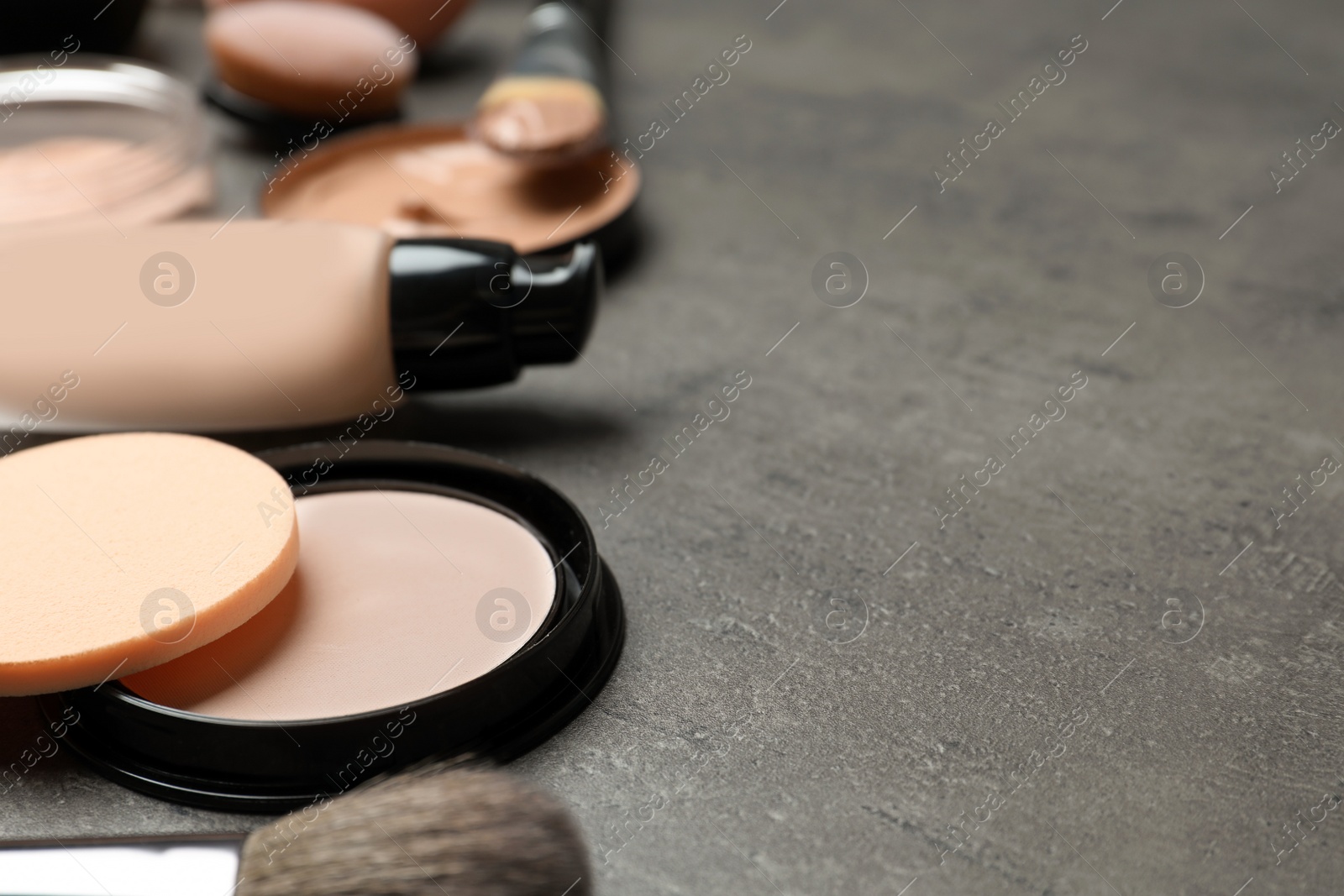 Photo of Composition with powder, skin foundation and beauty accessories on grey background. Space for text