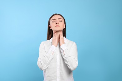 Photo of Young woman with sore throat on light blue background
