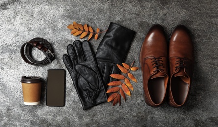 Photo of Flat lay composition with stylish black leather gloves, male shoes and dry leaves on grey table