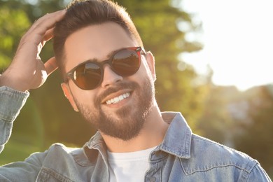 Photo of Handsome smiling man in sunglasses outdoors, space for text