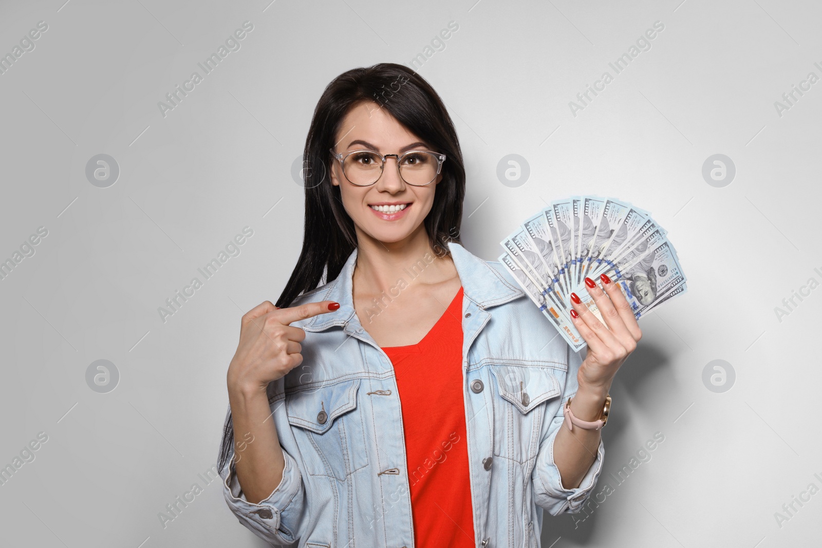 Photo of Portrait of stylish woman with money fan on light background