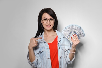 Photo of Portrait of stylish woman with money fan on light background
