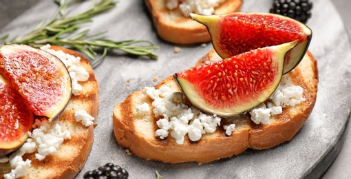 Bruschettas with figs and cheese served on board, closeup. Banner design 