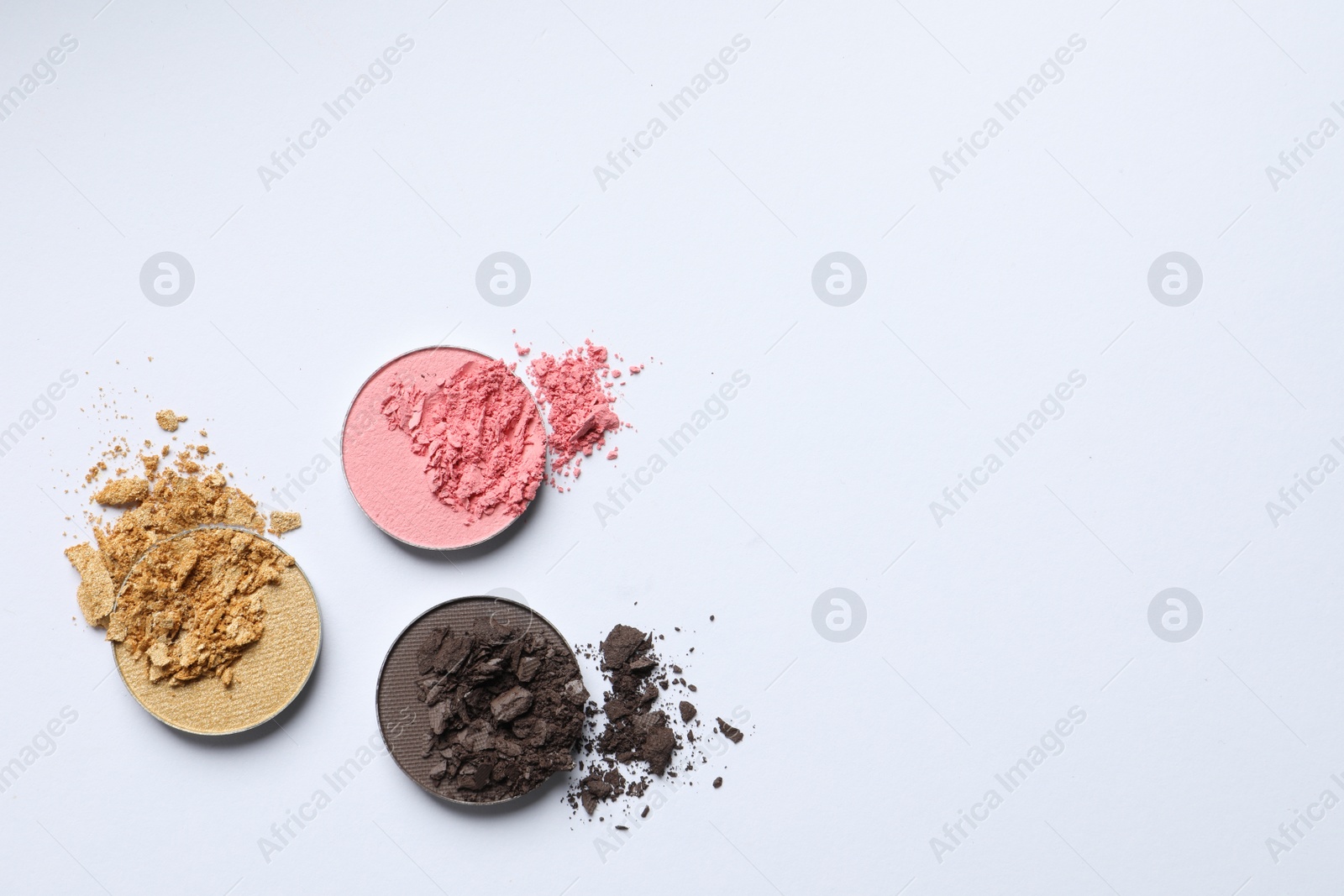 Photo of Different crushed eye shadows on white background, flat lay. Space for text