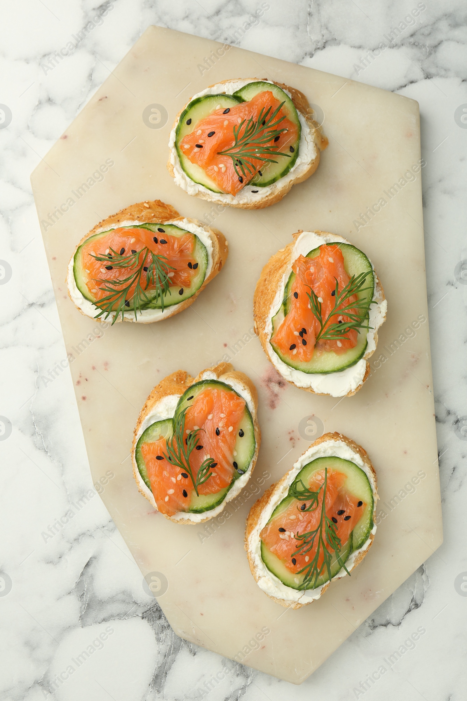 Photo of Tasty canapes with salmon, cucumber and cream cheese on white marble table, top view