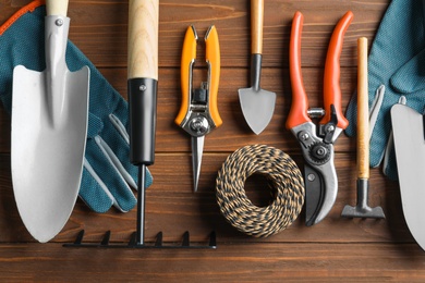 Flat lay composition with professional gardening tools on wooden background