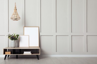 Photo of Simple room interior with console table, decor elements and empty wall. Space for design