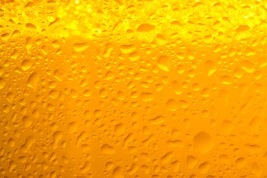 Photo of Glass of tasty cold beer with condensation drops as background, closeup