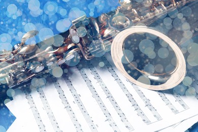 Image of Christmas and New Year music. Saxophone and music sheets on blue wooden table, bokeh effect