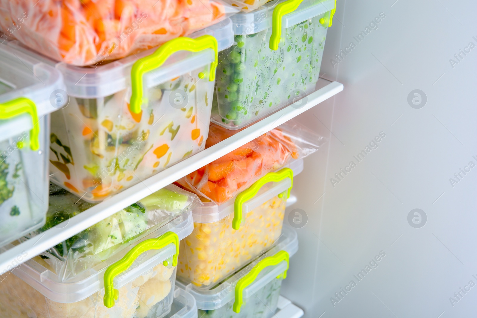 Photo of Containers with deep frozen vegetables in refrigerator