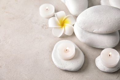 Photo of Beautiful spa composition with candles and stones on light background, space for text