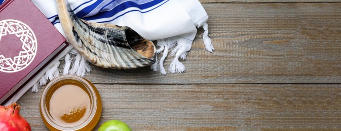 Honey, pomegranate, apples, shofar and Torah on wooden table, flat lay with space for text. Rosh Hashana holiday