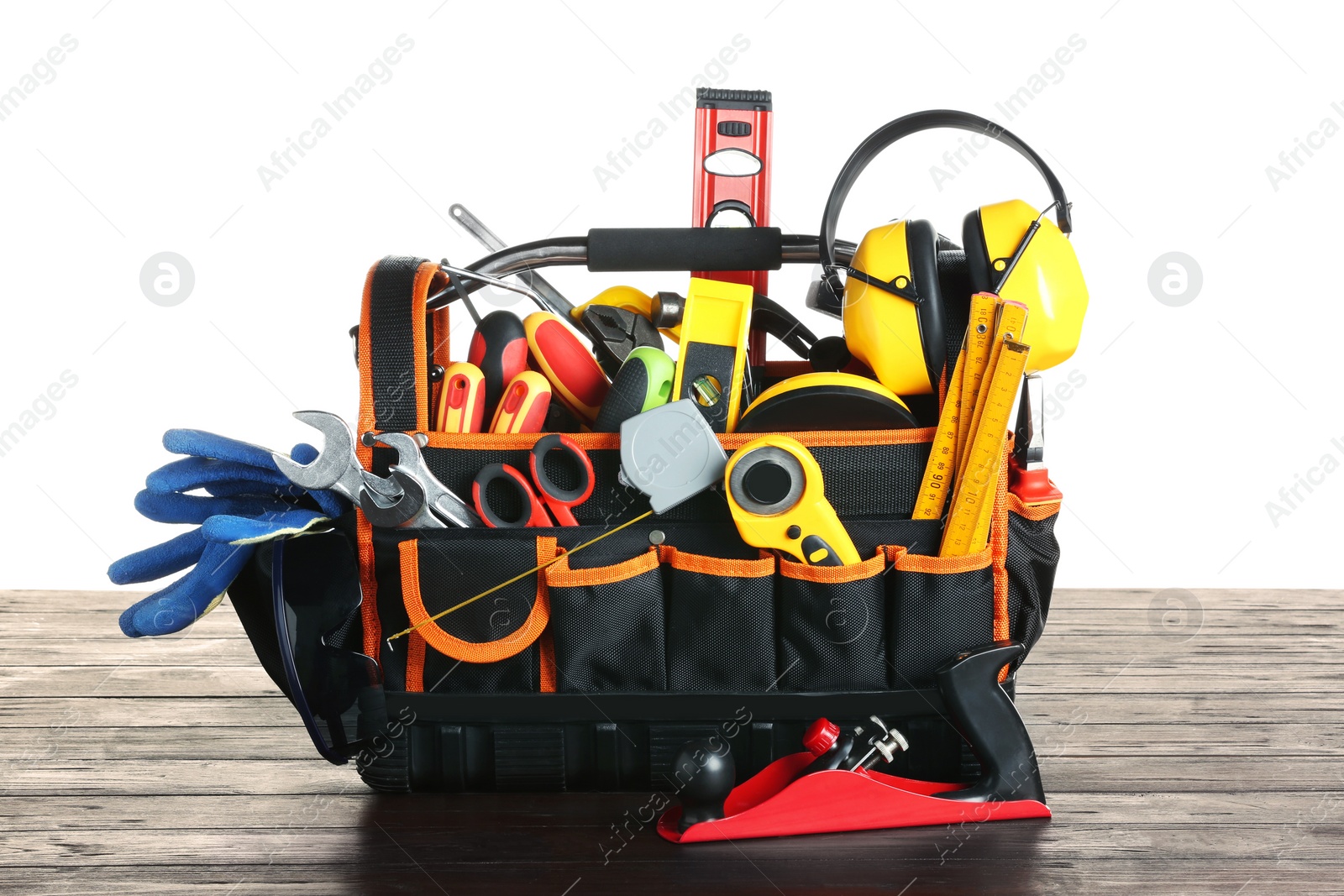 Photo of Bag with different tools on wooden table against white background