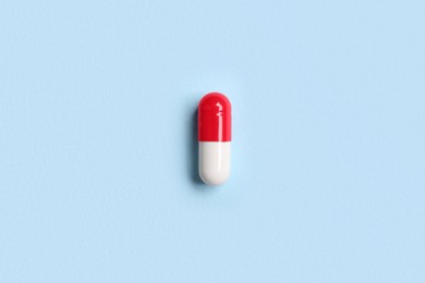 One pill on light blue background, top view