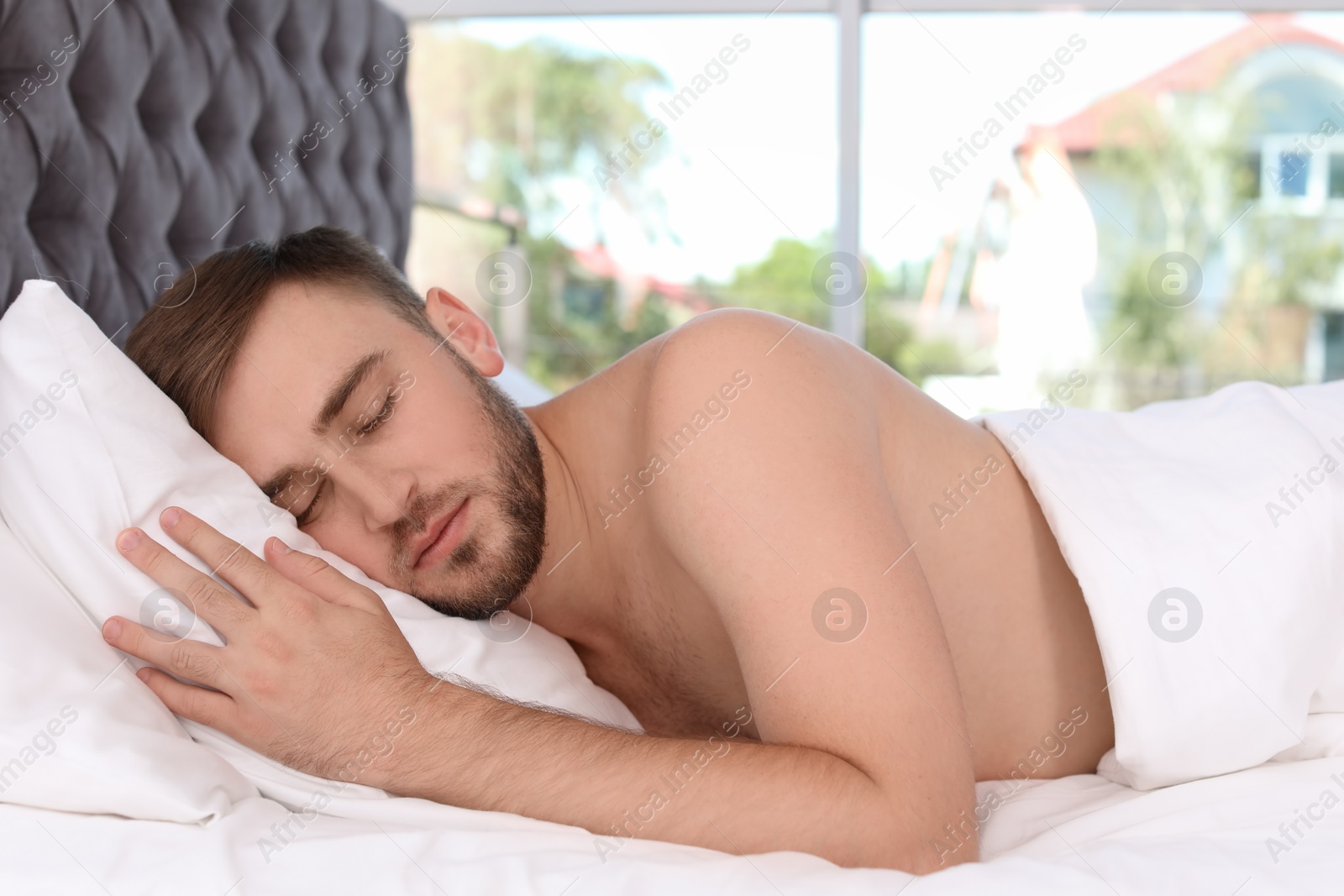 Photo of Young handsome man sleeping in bed at home. Early morning