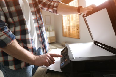 Photo of Man using modern multifunction printer in office, closeup