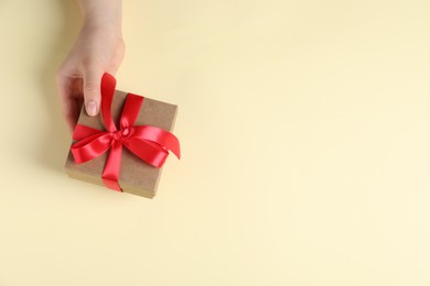 Photo of Woman with gift box on beige background, top view. Space for text