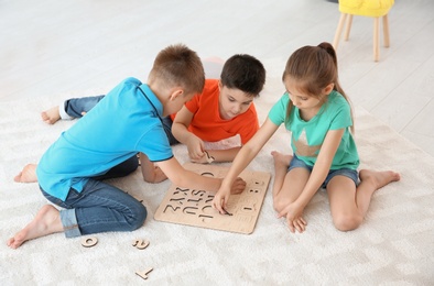 Photo of Cute little children playing together on floor, indoors