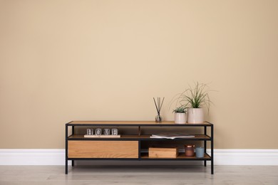 Photo of Modern TV cabinet with decor near beige wall. Space for design