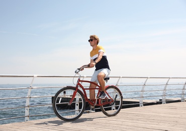 Attractive man riding bike near sea on sunny day