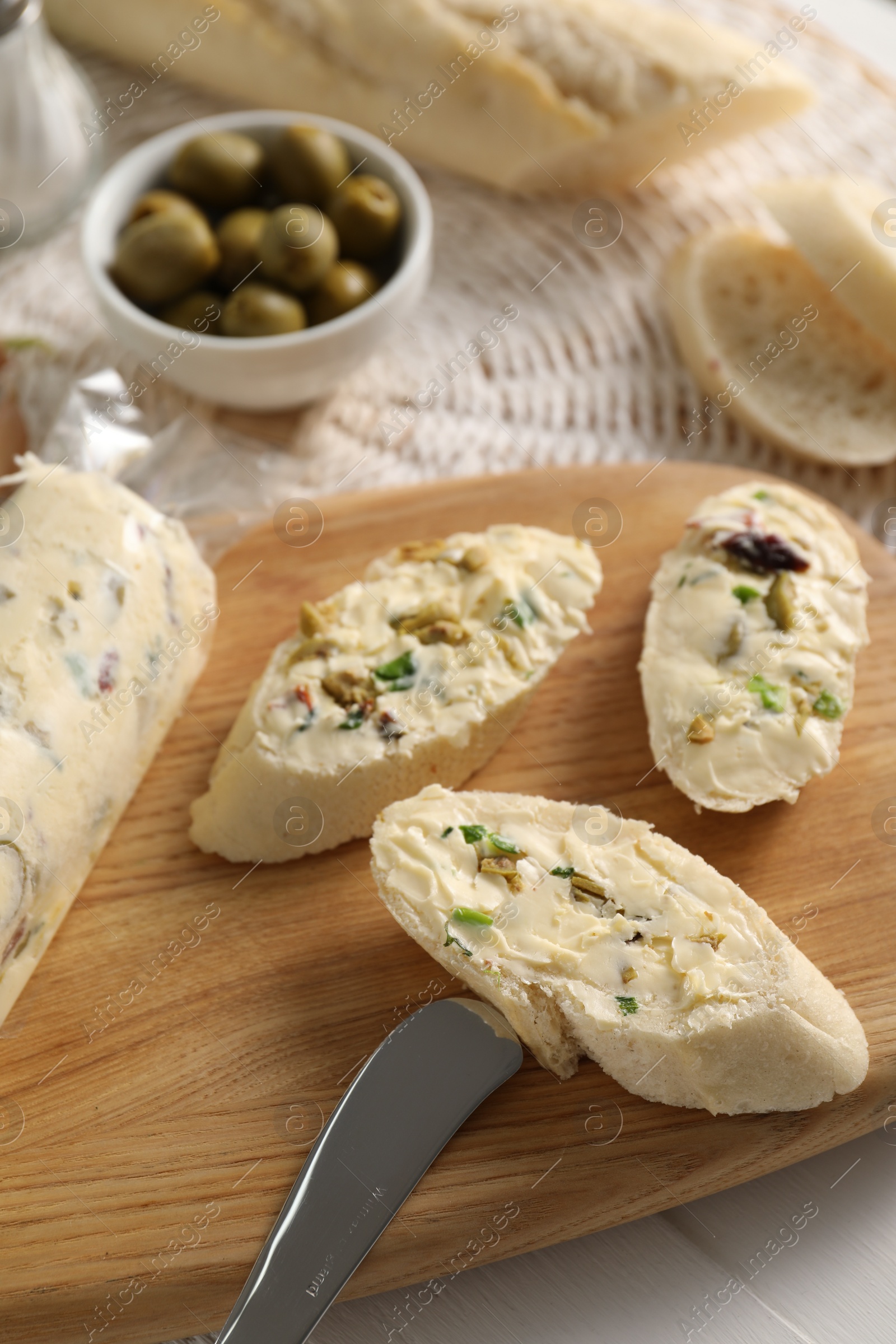 Photo of Tasty butter with olives, green onion, bread and knife on table