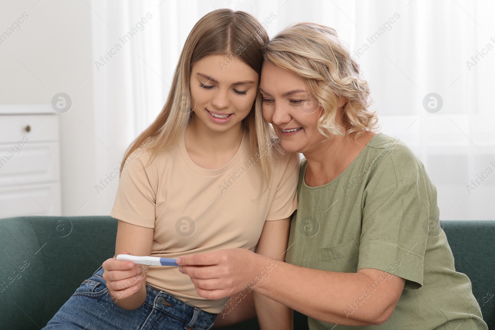 Photo of Young woman showing her mother pregnancy test at home. Grandparent reaction to future grandson