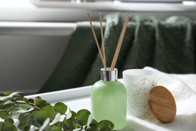 Photo of Reed air freshener and eucalyptus branches on tray indoors