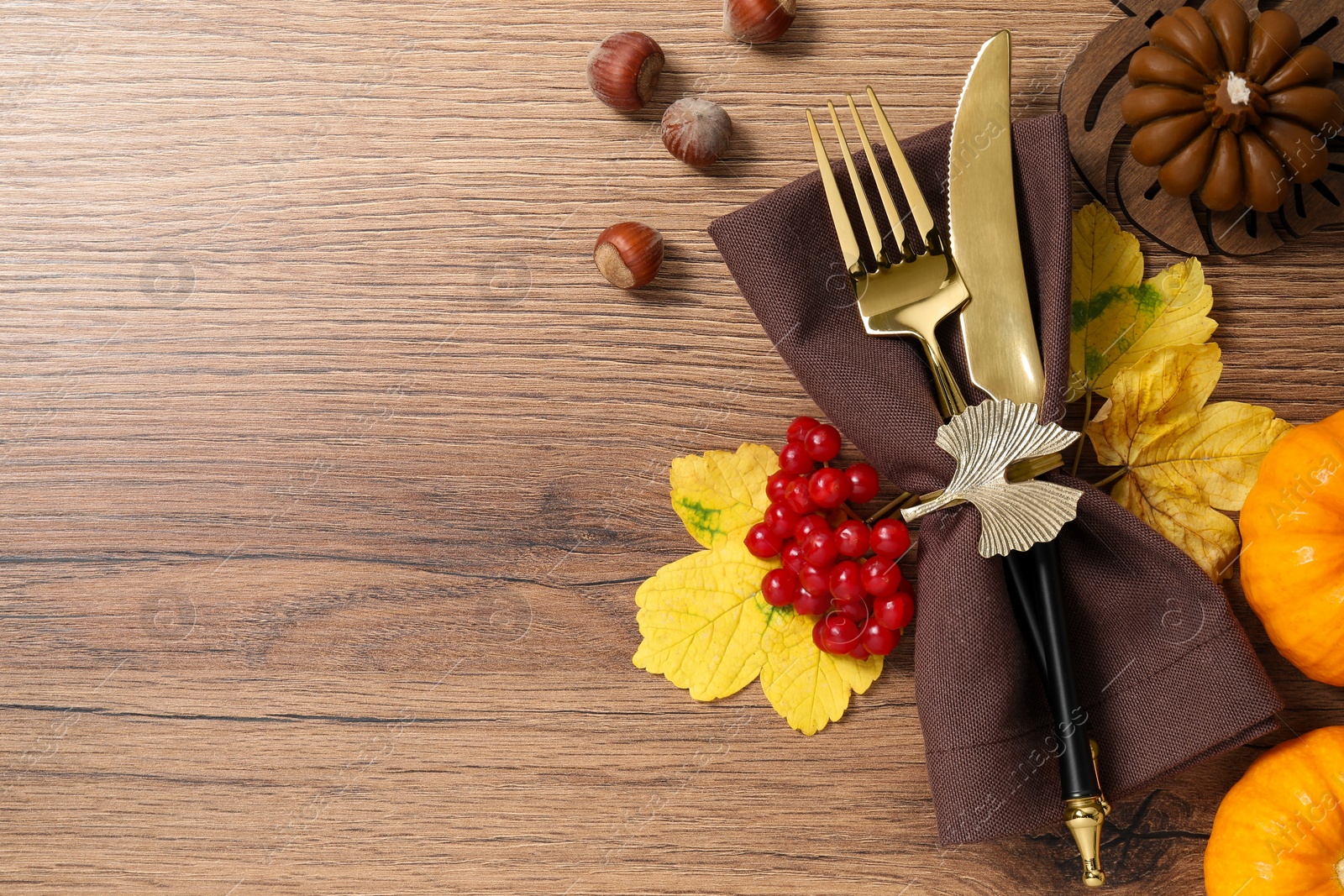 Photo of Thanksgiving table setting. Cutlery, napkin and autumn decor, flat lay with space for text