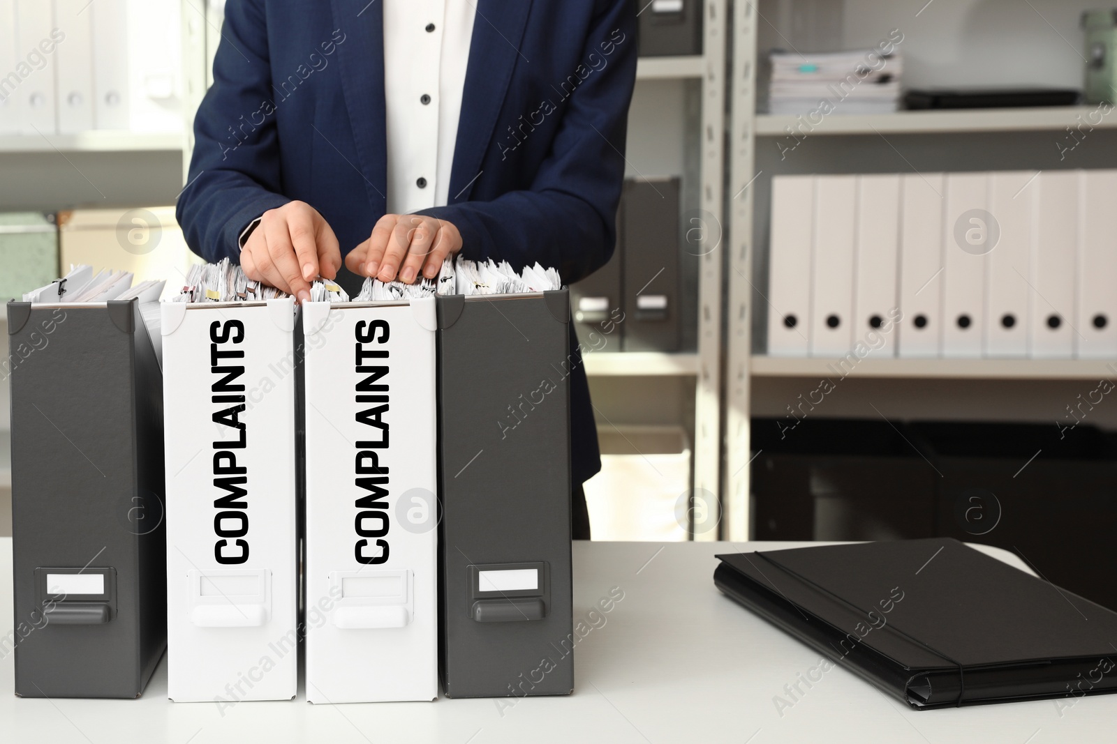 Image of Woman searching through documents in folder with Complaints label in office, closeup