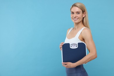 Slim woman holding scales on light blue background, space for text. Weight loss