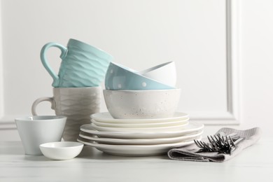 Beautiful ceramic dishware, cups and cutlery on white marble table