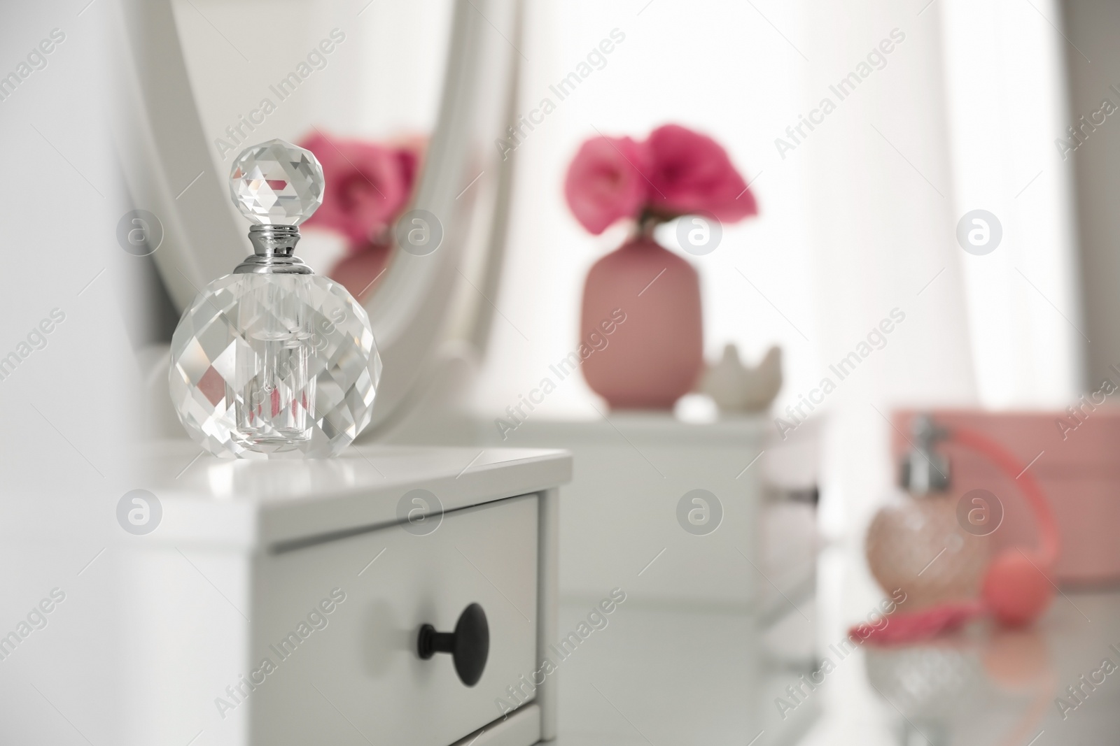 Photo of Bottle of perfume on white dressing table