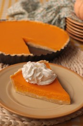 Piece of fresh homemade pumpkin pie with whipped cream on table