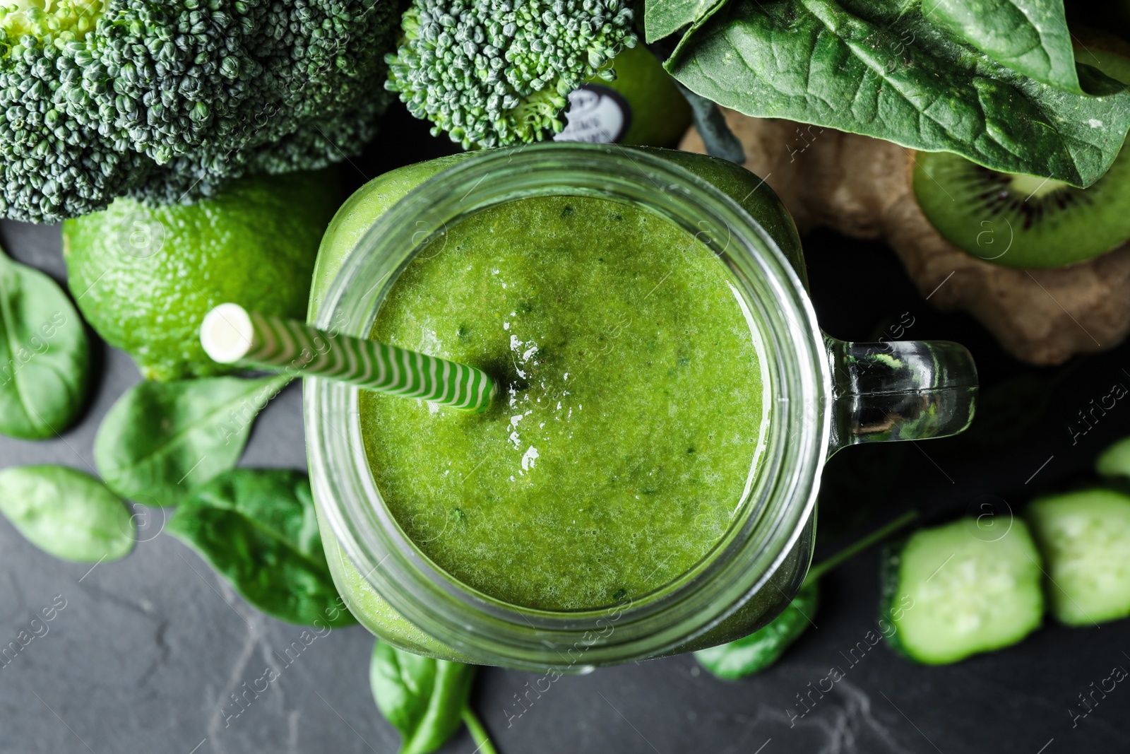 Photo of Delicious green juice and fresh ingredients on black table, flat lay