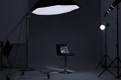 Photo of Casting call. Chair, clapperboard and different equipment in modern studio