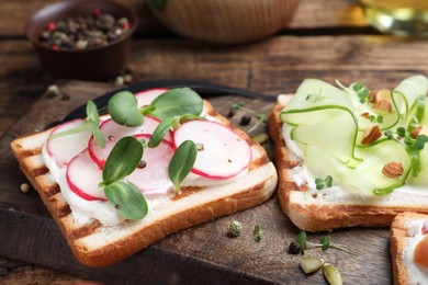 Photo of Different delicious sandwiches with microgreens on wooden board, closeup