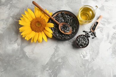 Photo of Flat lay composition with sunflower seeds, oil and flower on table