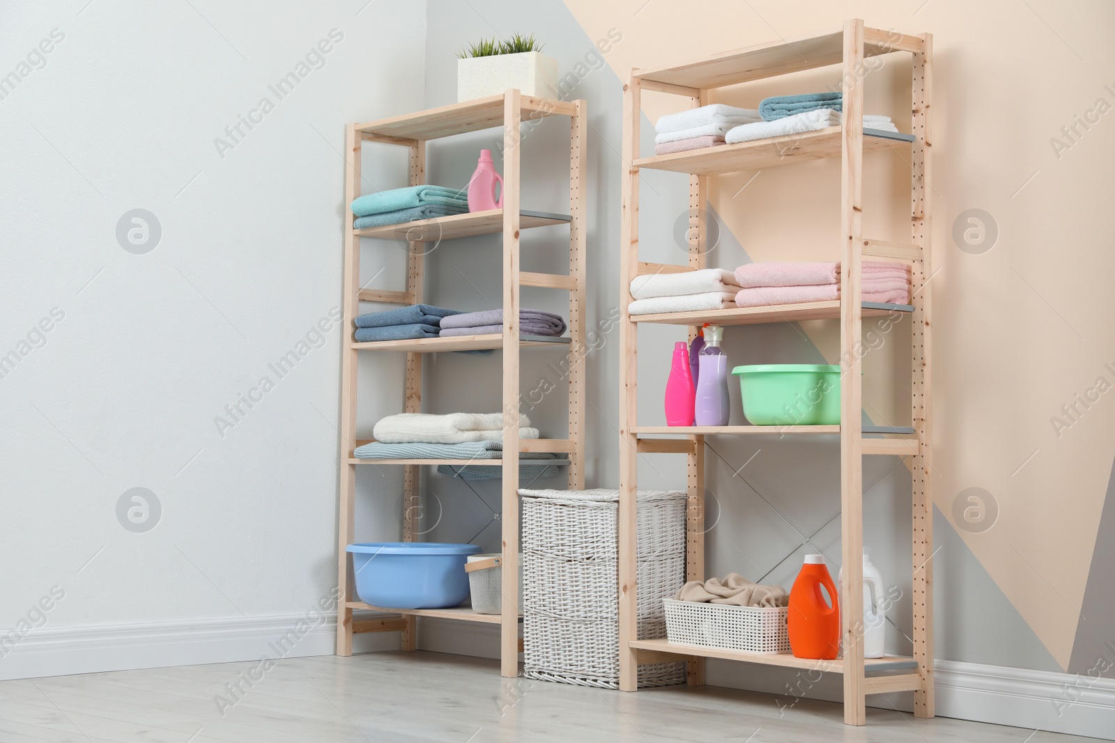 Photo of Wooden shelving units with clean towels and detergents in stylish room interior